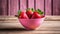 A pink bowl filled with red strawberries on a wooden table