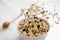 Pink bowl of fruit granola and honey over white wooden background, side view