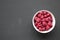 Pink bowl of raspberry on black background, top view. From above, overhead, flat lay.