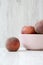 Pink bowl of ripe peaches on white wooden background, side view.