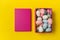 Pink box with colorful Easter eggs, bright yellow background. Copy space, top view