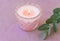 Pink burning candle in elegant crystal candle holder green silver dollar eucalyptus branch on lilac cotton table cloth. Romantic