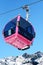 Pink cable car cabin over the snow mountain peak