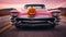 A pink Cadillac on the road, with an illuminated Halloween pumpkin on its hood