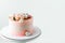 Pink cake decorated with pink rose flowers and merengue cookies on the white background