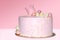 Pink cake for a girl with a decoration in the form of a crown and balls on an isolated background.