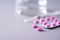 Pink capsule, pills, vitamins on grey background. Copy space. Bunch of drugs, cold flu treatment. Women disease