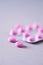 Pink capsule, pills, vitamins on grey background. Copy space. Bunch of drugs, cold flu treatment. Women disease