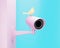 Pink CCTV security camera and yellow bird