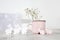 Pink ceramic milk mug with gypsophila and small plywood rabbits for decorating Easter table on a sunny morning