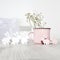 Pink ceramic milk mug with gypsophila and small plywood rabbits for decorating Easter table on a sunny morning