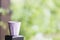 A pink ceramic mug with white spots resting on a wooden pole in the garden