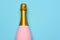 A Pink Champagne bottle on a blue teal background. Horizontal high angle shot