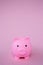 A pink childrens piggy bank on a pink background with copy space