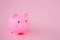 A pink childrens piggy bank on a pink background with copy space