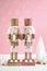 Pink Christmas nutcracker ornaments against a pink and white background.