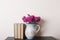 Pink chrysanthemum in a clay rarity vase and books on a wooden table