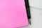 Pink closed notebook with pen