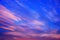 Pink clouds are floating on a bright blue sky. The evening horizon glows with multicolor.