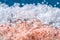 Pink coarse salt crystals on blue table. Himalaya salt. Background for advertising salty.