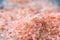 Pink coarse salt crystals on blue table. Himalaya salt. Background for advertising salty.