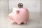 Pink coin bank on with a silver coin