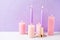 Pink color burning candles near by violet textured background.