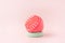 Pink color scalp massager on green stand against pink background