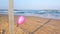 Pink color single balloon tied to a pole on the beach