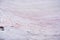 Pink colored frozen snow melting under the bright sun