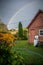 Pink country house in a village in an autumn garden with a blue sky and a rainbow in the sky.vertical photo