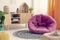 Pink cozy pouf in the middle of elegant natural kid`s room with wooden furniture and ethno design