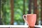 pink cup on the background of the forest and the lake. The girl makes tea or coffee with a croissant in the morning