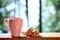 pink cup on the background of the forest and the lake. The girl makes tea or coffee with a croissant in the morning