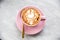 Pink cup of cappuccino with swan latte art on marble table background