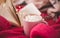 Pink cup of coffee with marshmellow and open book on Christmas lights on knitted bright red sweater background