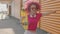 A pink curly girl is having fun or relaxing and enjoying summer. Casual teenager is walking on a city street. Happy and