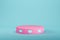 Pink cylindrical pedestal on light blue background for product display