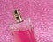 Pink delicate perfume spray bottle on fabric shiny background