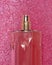 Pink delicate perfume spray bottle on fabric shiny background