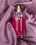 Pink delicate perfume spray bottle on fabric silk background