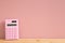 Pink digital calculator on wooden desk with pink background