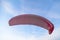 Pink dome of paraglider flying in blue bright sky