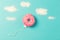 Pink donut on blue background, creative food minimalism, donut in a shape of balloon in the sky with clouds made of sugar