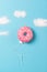 Pink donut on blue background, creative food minimalism, donut in a shape of balloon in the sky with clouds made of sugar, top