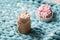 Pink donut with marshmallow and hot chocolate in glass cup on blue merino knit blanket. Lights on background