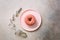 Pink donut on plate, measuring tape over grey concrete background. Diet concept. Weight lost after holidays