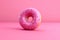 Pink donut topped with icing on paper background, glazed doughnut with sprinkles, crumbs. Unhealthy high-calorie food. Image is AI