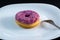 pink doughnut with powder on a white plate with a fork