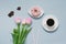 Pink doughnut on a saucer, pink tulips and coffee on a blue background. Romantic Valentine`s day Breakfast in bed for your loved